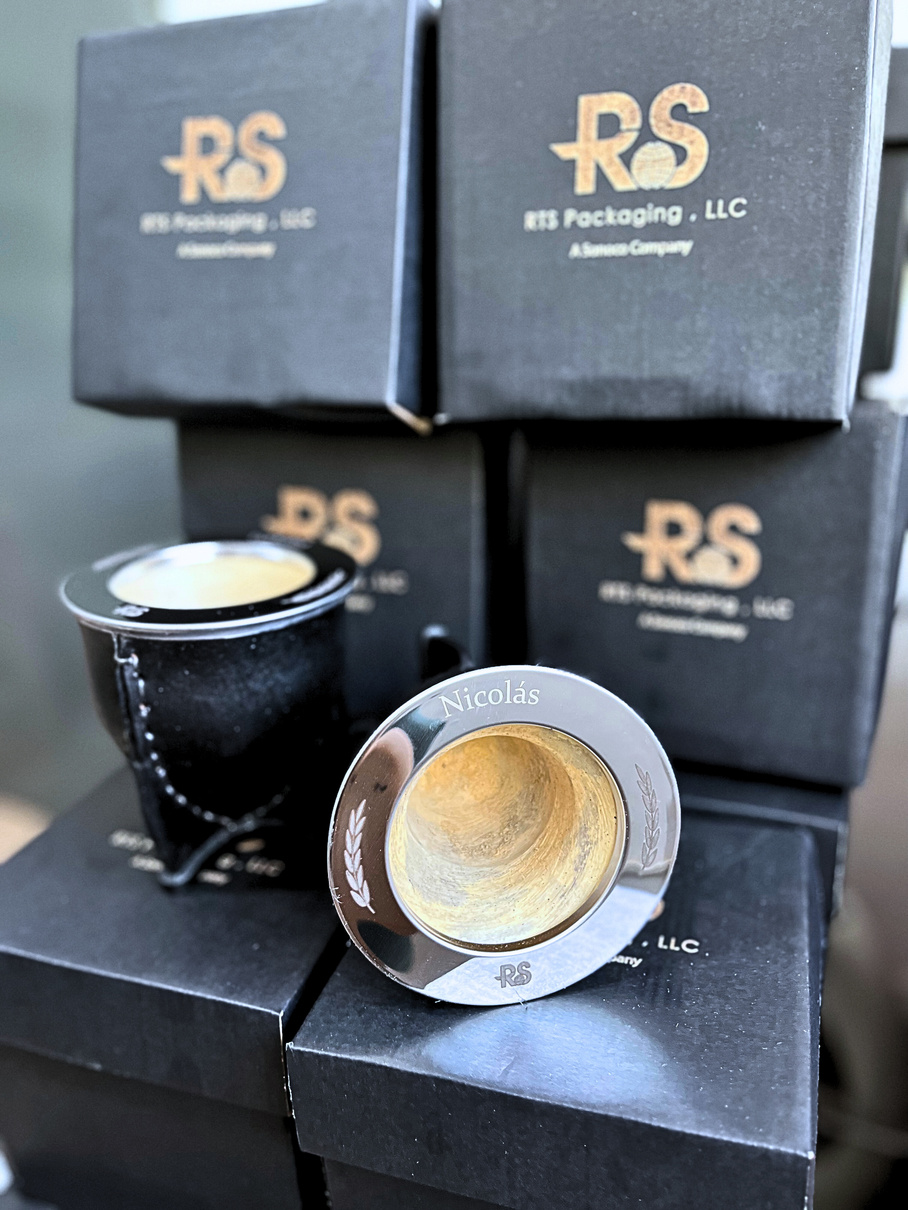 Cajas de regalo empresarial RS Packaging junto a un mate grabado con el nombre Nicolás